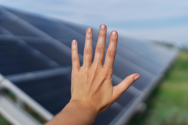 Mão humana no painel solar com fundo desfocado conceito de fonte de eletricidade fotovoltaica alternativa