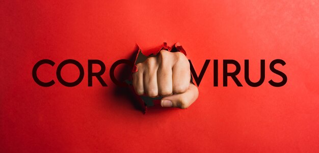 Foto mão humana rasgando papel vermelho com a palavra coronavírus