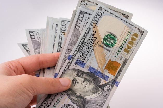 Mão humana segurando notas de dólar americano em fundo branco