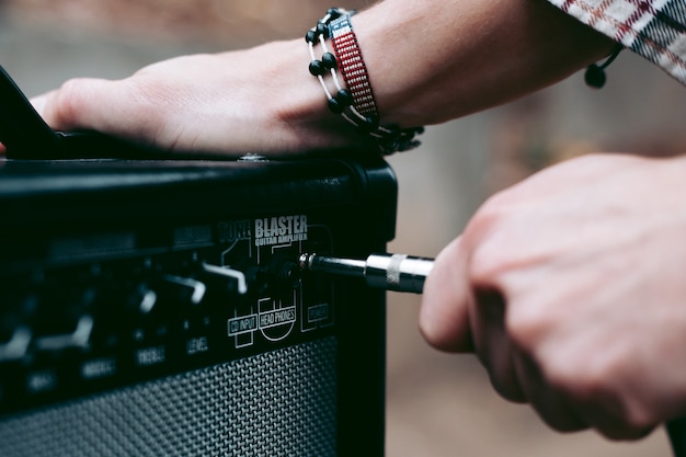 Mão insere um conector de cabo em um amplificador combo para guitarra elétrica