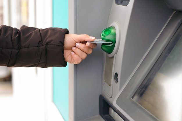 Foto mão inserindo o cartão do caixa eletrônico na máquina do banco para retirar dinheiro