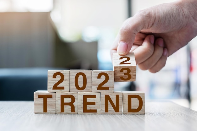 Mão lançando o bloco 2022 a 2023 texto TREND na mesa Resolução ideia objetivo motivação reiniciar negócios e conceitos de feriado de Ano Novo