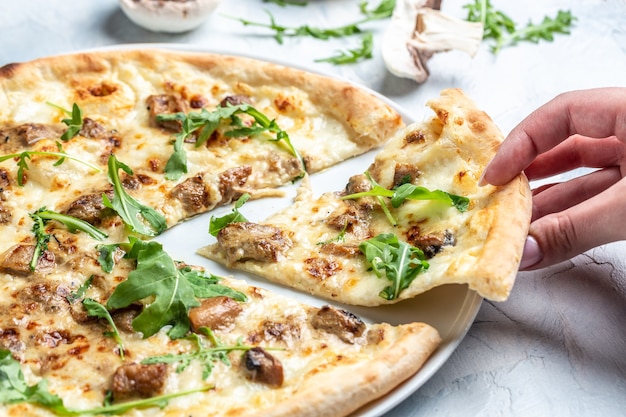 Mão levando pizza de cogumelos fatiados com mussarela e rúcula. Pizza italiana. Cozinha italiana. vista do topo