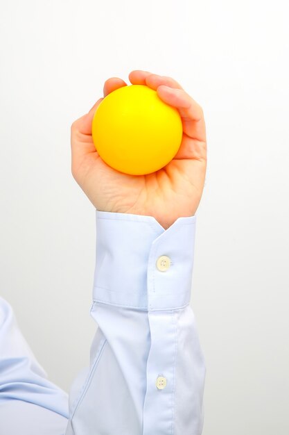 Mão masculina com uma bola amarela em uma superfície branca