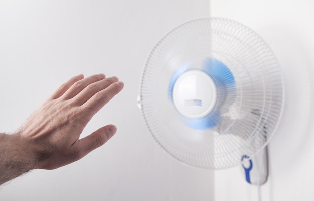 Mão masculina com ventilador elétrico em casa