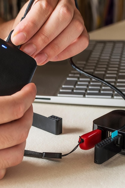 Mão masculina conectando o disco rígido com cabo USB ao laptop e divisor usb