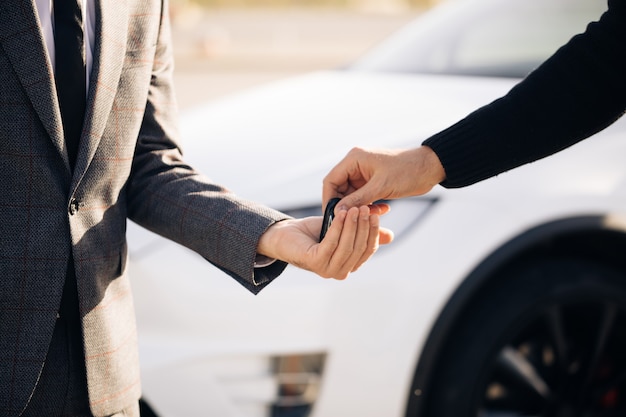 Mão masculina dá as chaves de um carro para mão masculina na concessionária de automóveis close-up