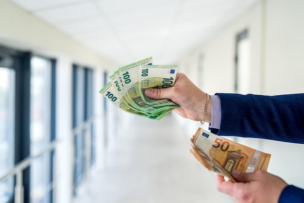 Mão masculina dando notas de euro no conceito de finanças do centro de escritório