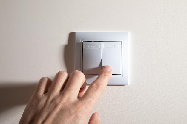 Mão masculina desligando ou ligando o interruptor de luz