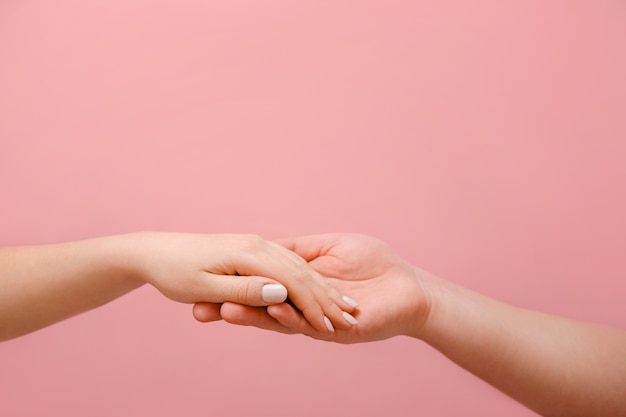 mão masculina e feminina em uma parede rosa