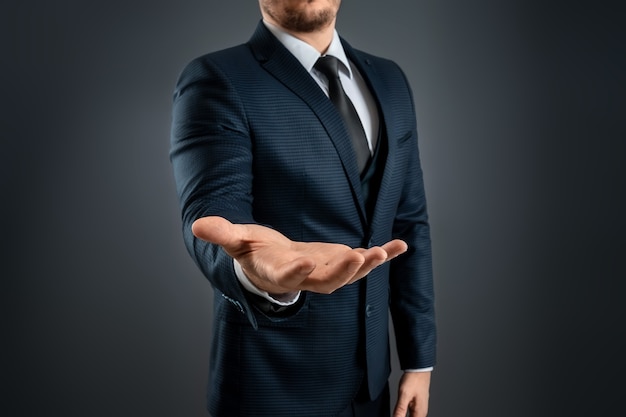 Mão masculina em um terno mostra um gesto com a palma para cima em um fundo cinza. Conceito de pedido, falência, close-up.