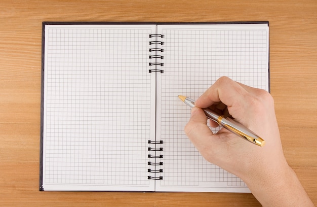 Mão masculina escrevendo a caneta em um caderno marcado