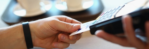 Mão masculina insere cartão de crédito de plástico no terminal de pagamento