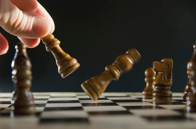 Imagem conceitual de estratégia e poder com peças de xadrez de  posicionamento de mão masculina na placa de madeira rústica.