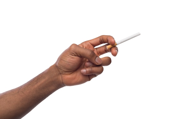 Mão masculina negra segurando um cigarro, isolado em um fundo branco. Mau hábito, conceito de fumar