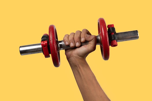 Mão masculina preta segurando um velho haltere vermelho isolado em fundo amarelo