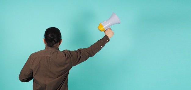 Mão masculina segura o megafone e usa uma camisa azul marinho com fundo verde, menta ou azul Tiffany.