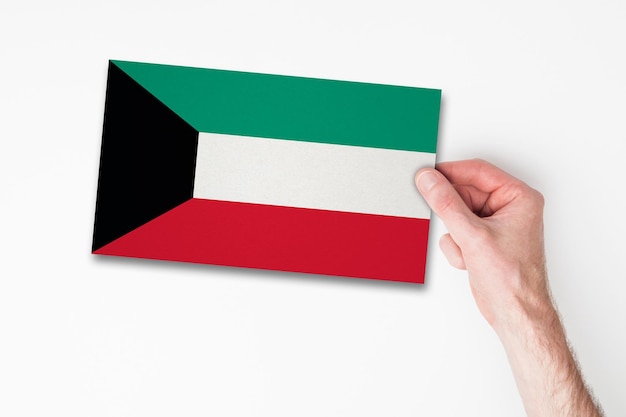 Mão masculina segurando a bandeira do kuwait