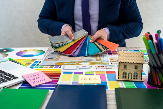 Mão masculina segurando amostras de cores com perspectiva interior. mão do designer de interiores trabalhando com o esboço do apartamento, amostras de materiais e cores