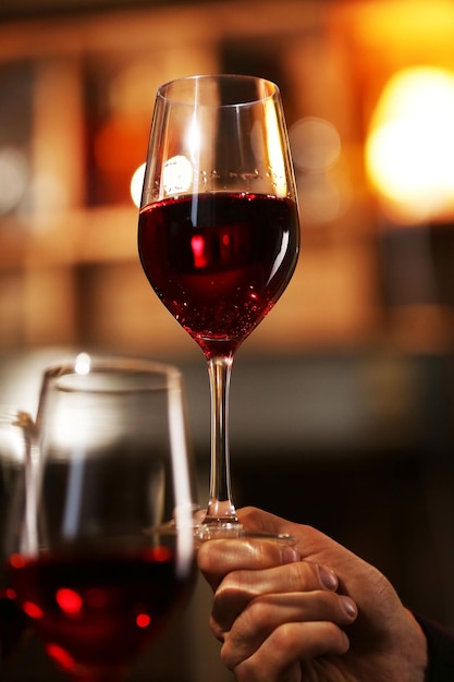 Mão masculina segurando copo de vinho no bar
