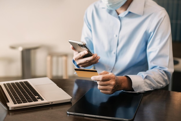 Mão masculina segurando laptop smartphone e usando cartão de crédito para compras onlineconceito de compras online