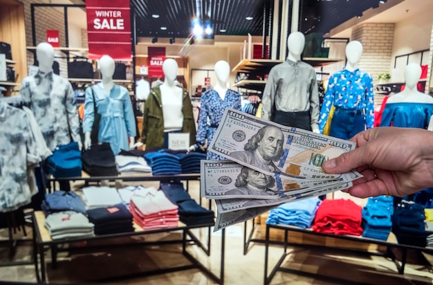 Mão masculina segurando o dólar na loja de roupas para compra. dinheiro