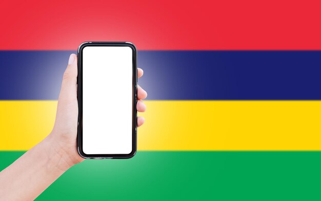 Mão masculina segurando smartphone com espaço em branco na tela no fundo da bandeira desfocada da Maurícia Closeup view