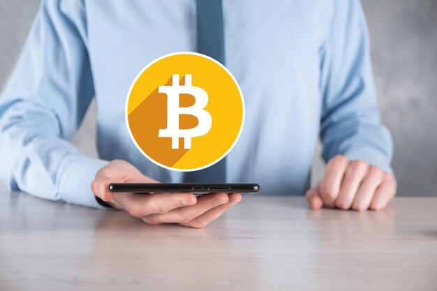 Mão masculina segurando um ícone de bitcoin em fundo cinza. Bitcoin Cryptocurrency Digital Bit Coin BTC Moeda Tecnologia Negócios Internet Conceito