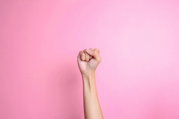 Mão mostrando punho ou perfurando o ar sobre fundo rosa Símbolo de protesto