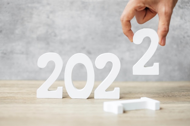 Mão mudar o número de 2021 para 2022 na mesa. conceitos de planejamento, finanças, resolução, estratégia, solução, objetivo, negócios e feriado de ano novo