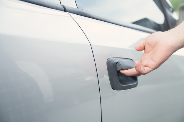 Mão na alça. Mão de homem abrindo a porta de um carro