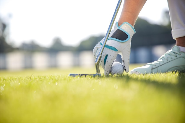 Mão na luva colocando a bola de golfe no tee