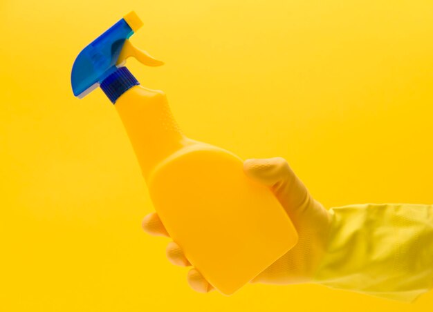 Mão na luva de borracha amarela com produto de limpeza