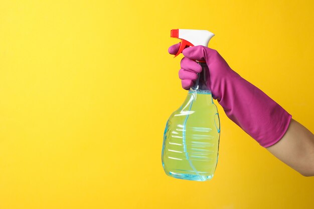 Mão na luva de limpeza segure limpador de janelas em amarelo, espaço para texto