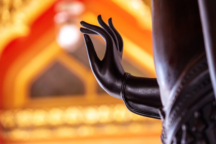 Foto mão negra da estátua de buda com luz amarela.