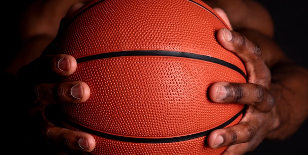Mão negra segurando bola de basquete