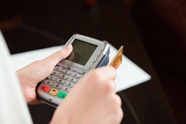 Mão passando o cartão de débito no terminal pos