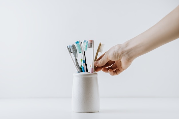 Foto mão pega escova de dentes ecológica de um copo branco