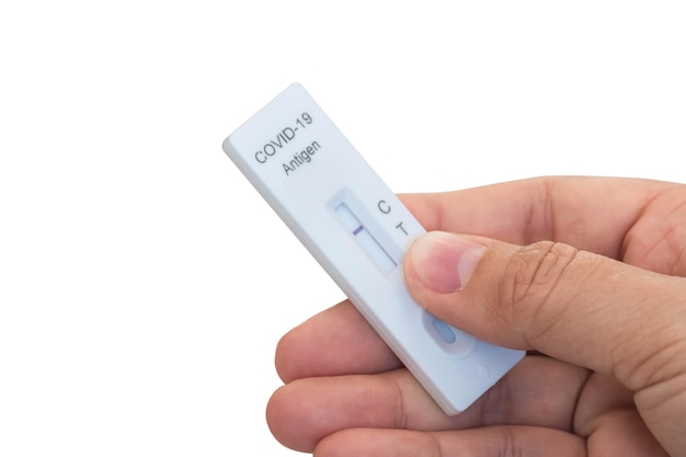 Mão pegando resultados de testes de saliva mostrando 1 linha em fundo branco com traçado de recorte