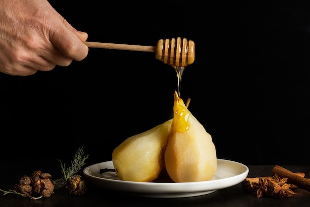 Mão pingando mel em peras assadas