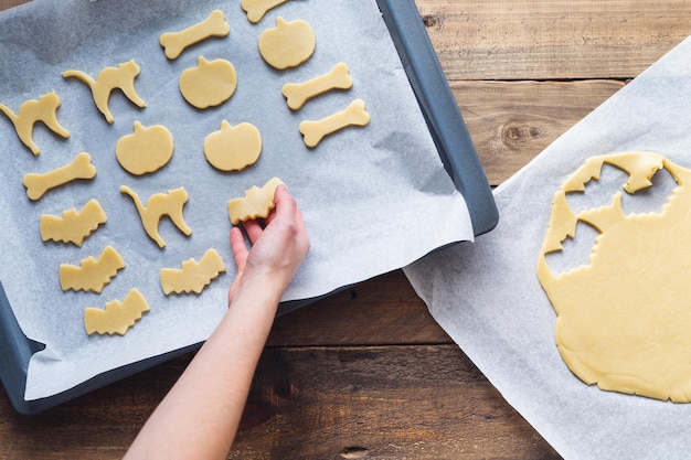 Mão preparando biscoitos em diferentes formas para o espaço de cópia de Halloween