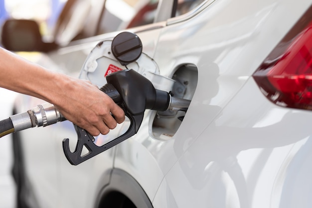 Mão, reabastecendo o carro com combustível, close-up, equipamento de bombeamento de gás no posto de gasolina.