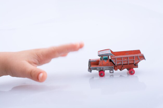 Foto mão recortada alcançando pista de despejo de brinquedo contra fundo branco