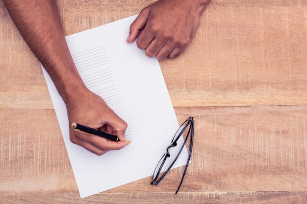 Mão recortada de empresário escrevendo no papel na mesa no escritório