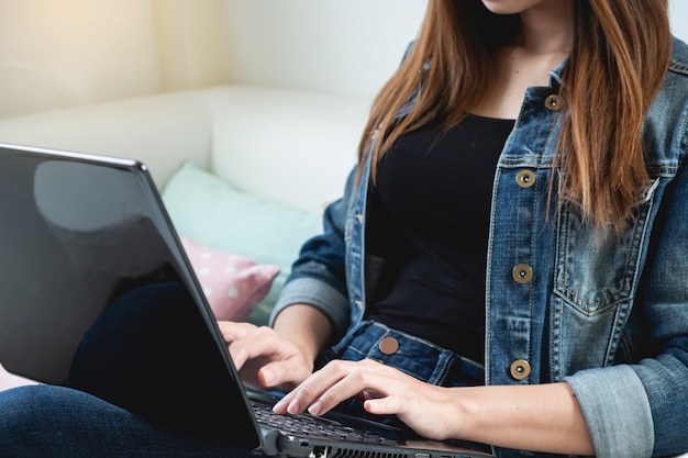 Mão recortada de mulher usando laptop em casa