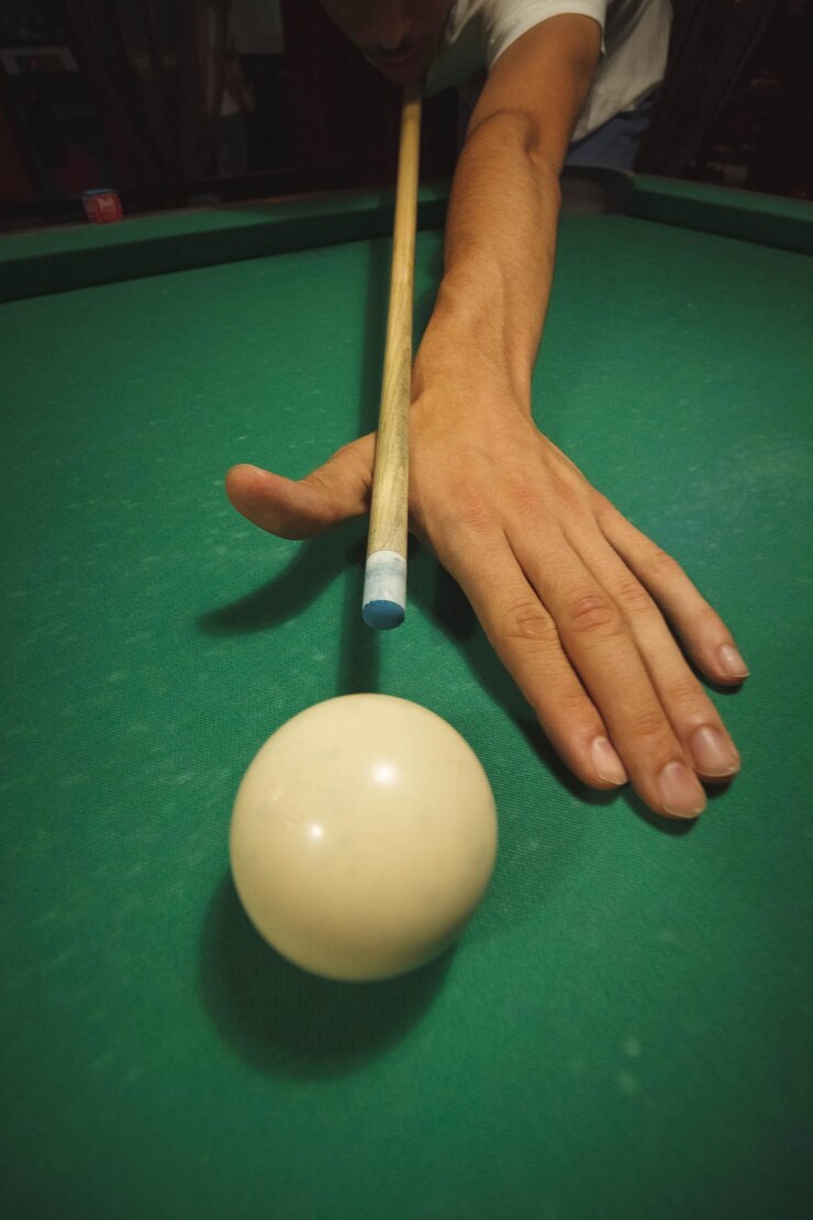 Foto mão recortada de pessoa segurando taco de bilhar por bola na mesa