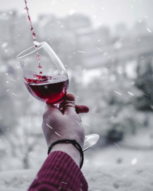 Foto mão recortada de pessoa segurando vinho vermelho em copo ao ar livre