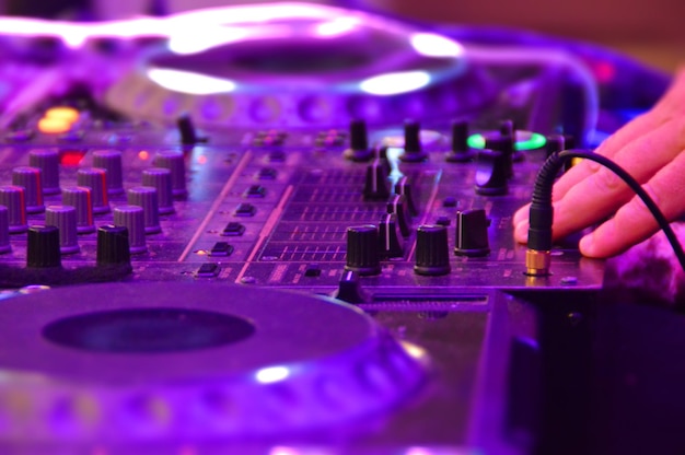 Mão recortada de um DJ a operar um misturador de som