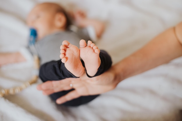 Mão recortada do pai segurando os pés do bebê na cama