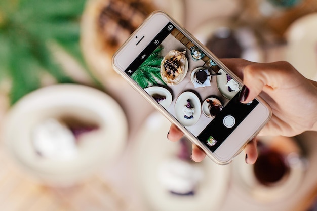 Foto mão recortada fotografando comida através de telefone celular